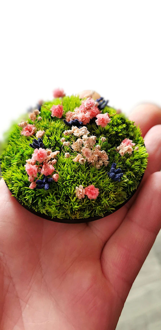 Getrocknete Blumen in einem kleinen runden Bild mit buntem Grün und floralen Akzenten, handgehalten für Dekoration.