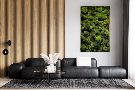 Echtes Moosbild "Moose Mix" in modernem Wohnzimmer mit schwarzem Sofa und Holzwand.