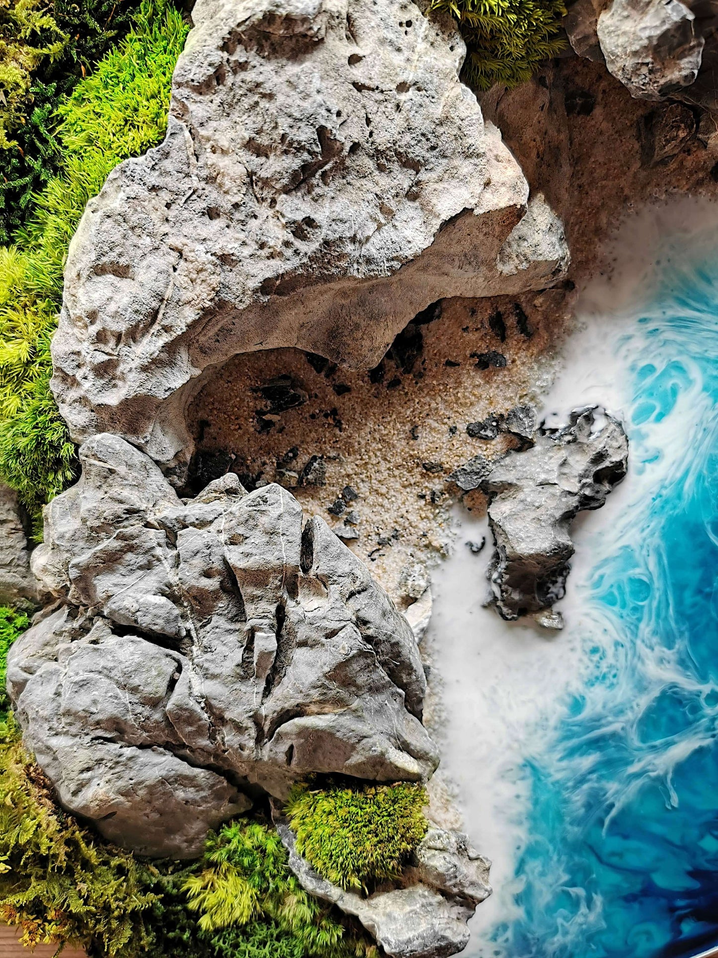 Detail of 'Autumn Coast' artwork showing textured rocks and vibrant blue epoxy resin waves.