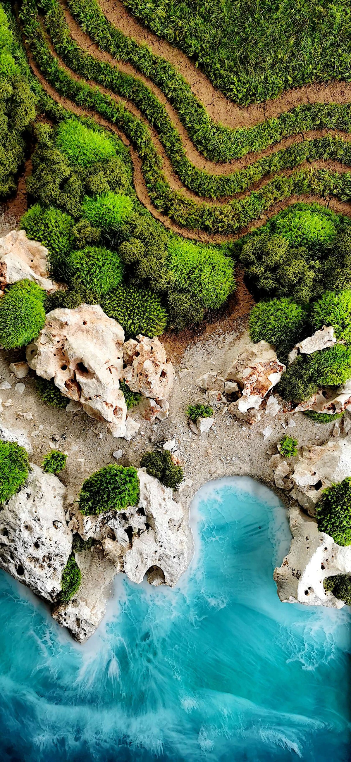 Aerial view of a coastal landscape with rocky cliffs, lush greenery, and turquoise waters.