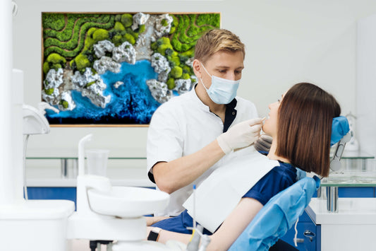 Zahnarzt behandelt Patientin mit Wandbild 'Ocean Coast' im Hintergrund, das eine entspannende Atmosphäre schafft.