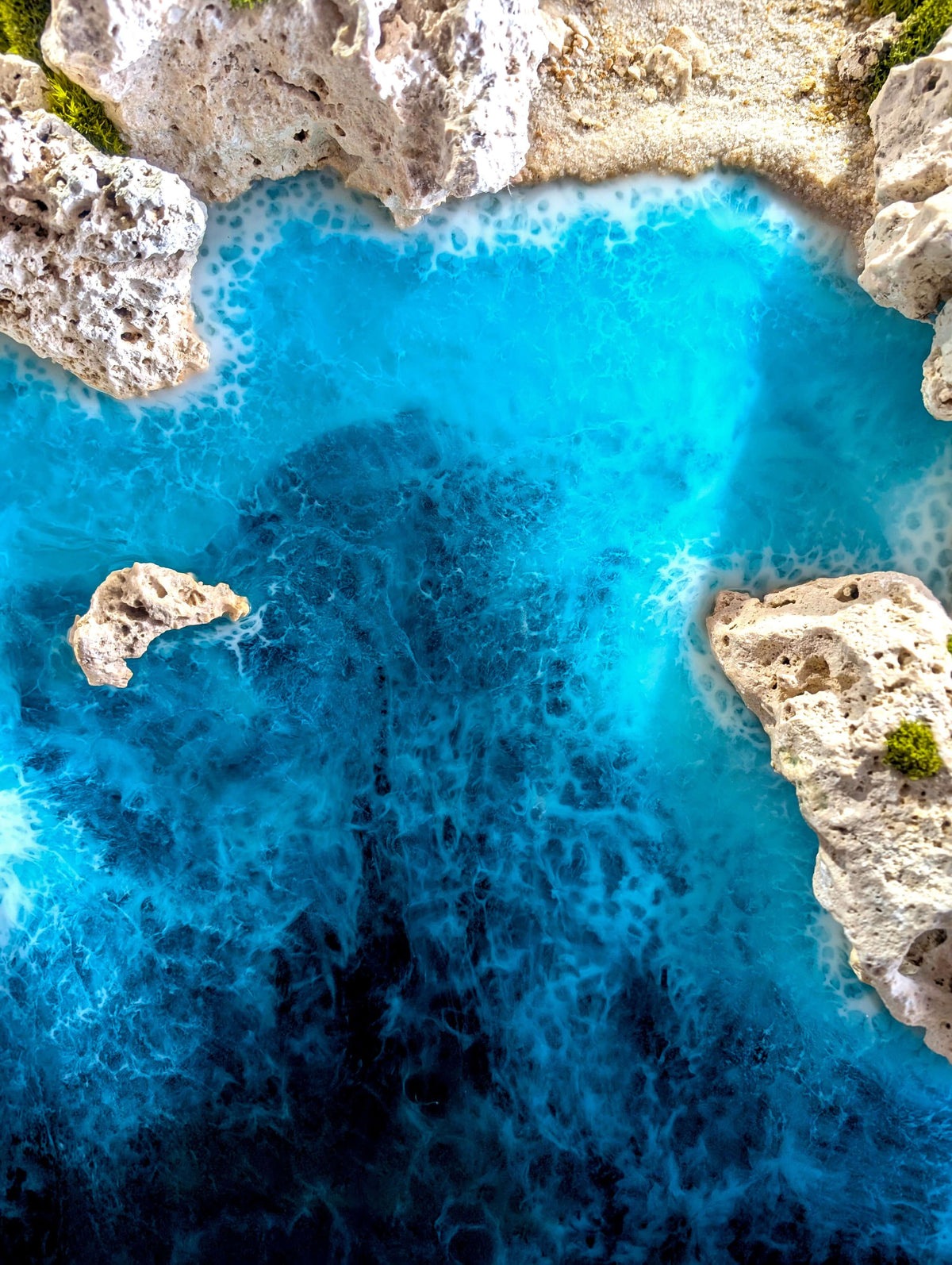Aerial view of vibrant turquoise water with rocky edges, ideal for maritime-themed decor.