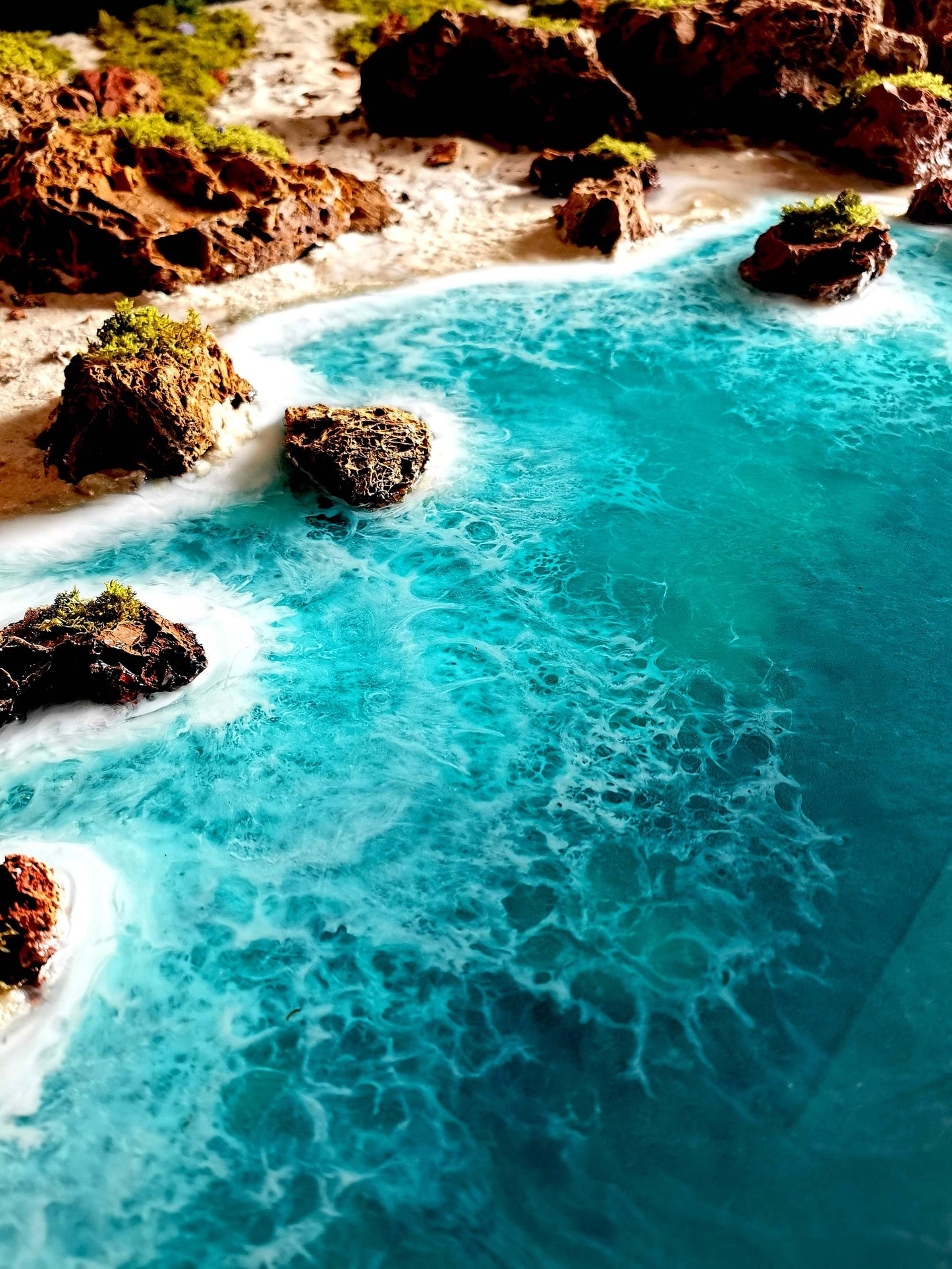 Diorama of Algarve coastline with turquoise waters, rocks, and lush greenery in handcrafted wall art.
