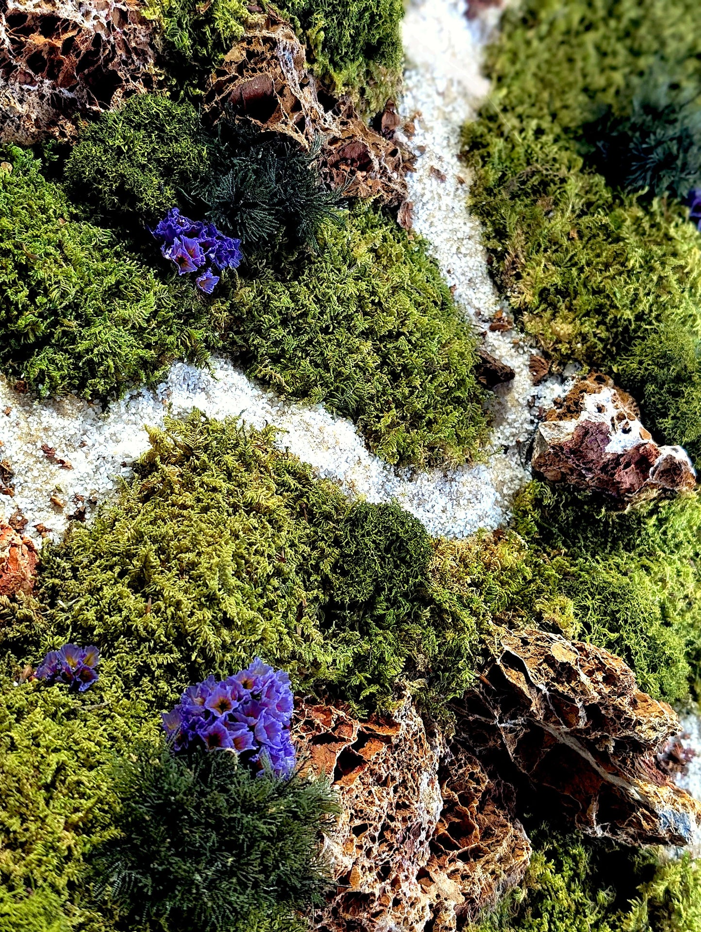 Detailaufnahme von grünem Moos und lila Blumen in einem handgefertigten Wandkunst-Diorama "Portugal Algarve".