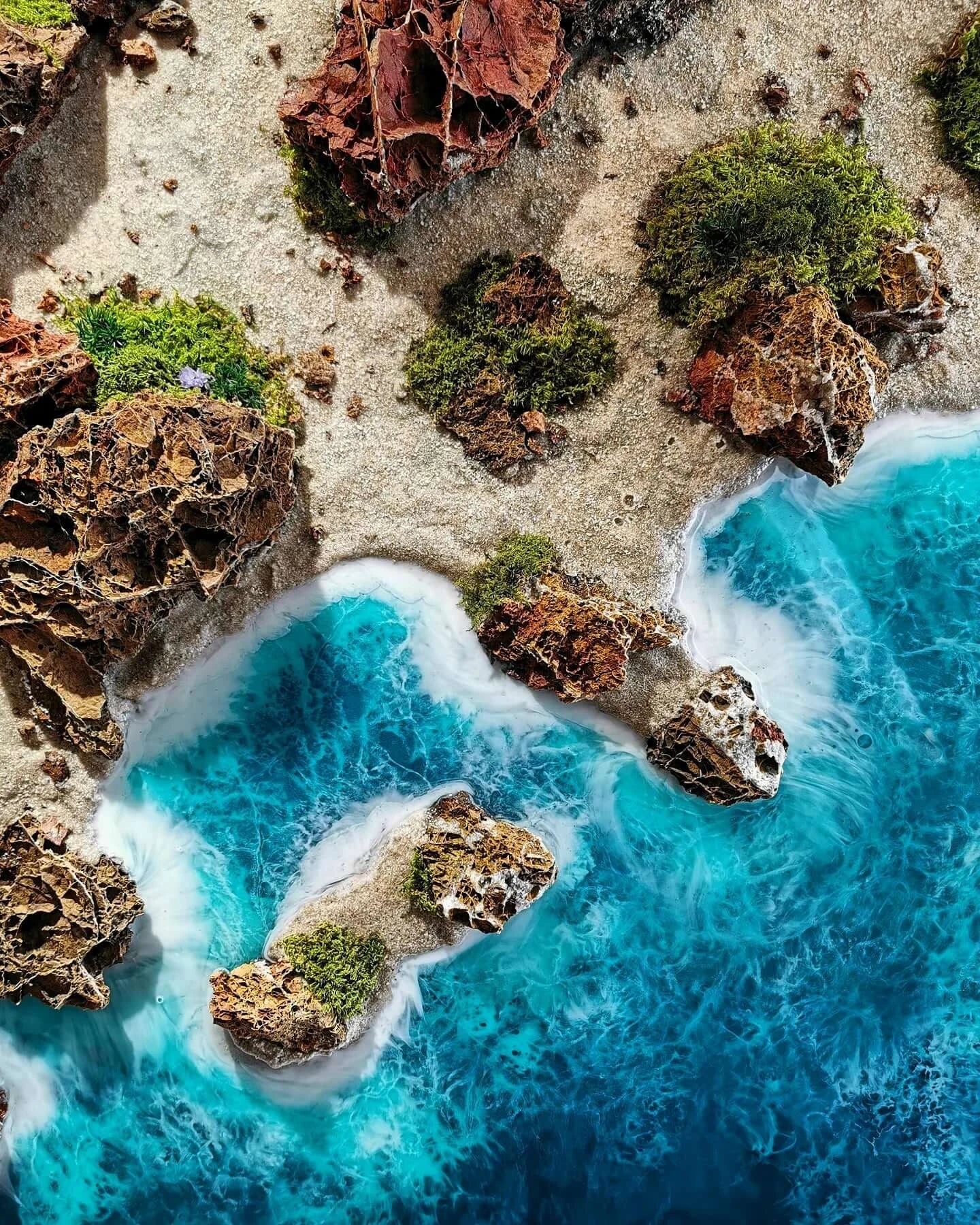 Aerial view of Algarve coastline featuring vibrant blue waters, rocky formations, and lush greenery.