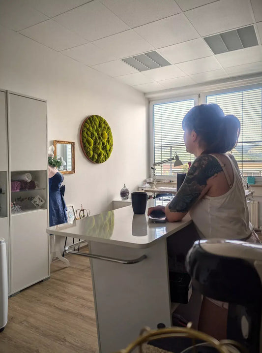Person admiring round moss artwork "Lime Green" in a stylish interior setting.