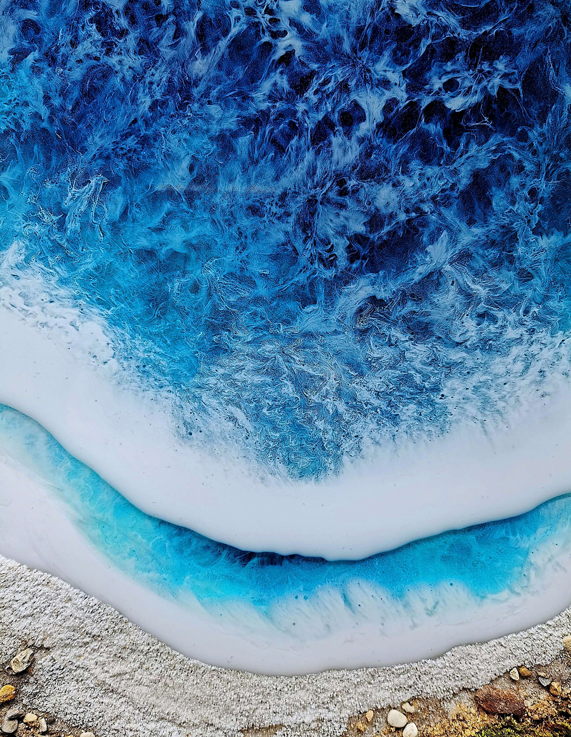 Aerial view of vibrant blue ocean waves meeting a sandy beach, showcasing serene coastal beauty.